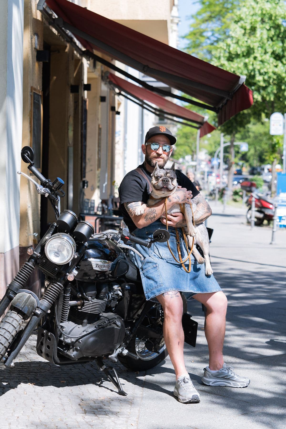 Alessandro sitzt mit Fred im Arm auf seinem Café Racer vor Tirelli's