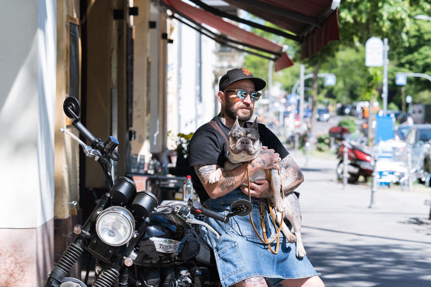 Alessandro mit Fred, seiner Französischen Bulldogge, auf dem Motorrad vor dem Laden