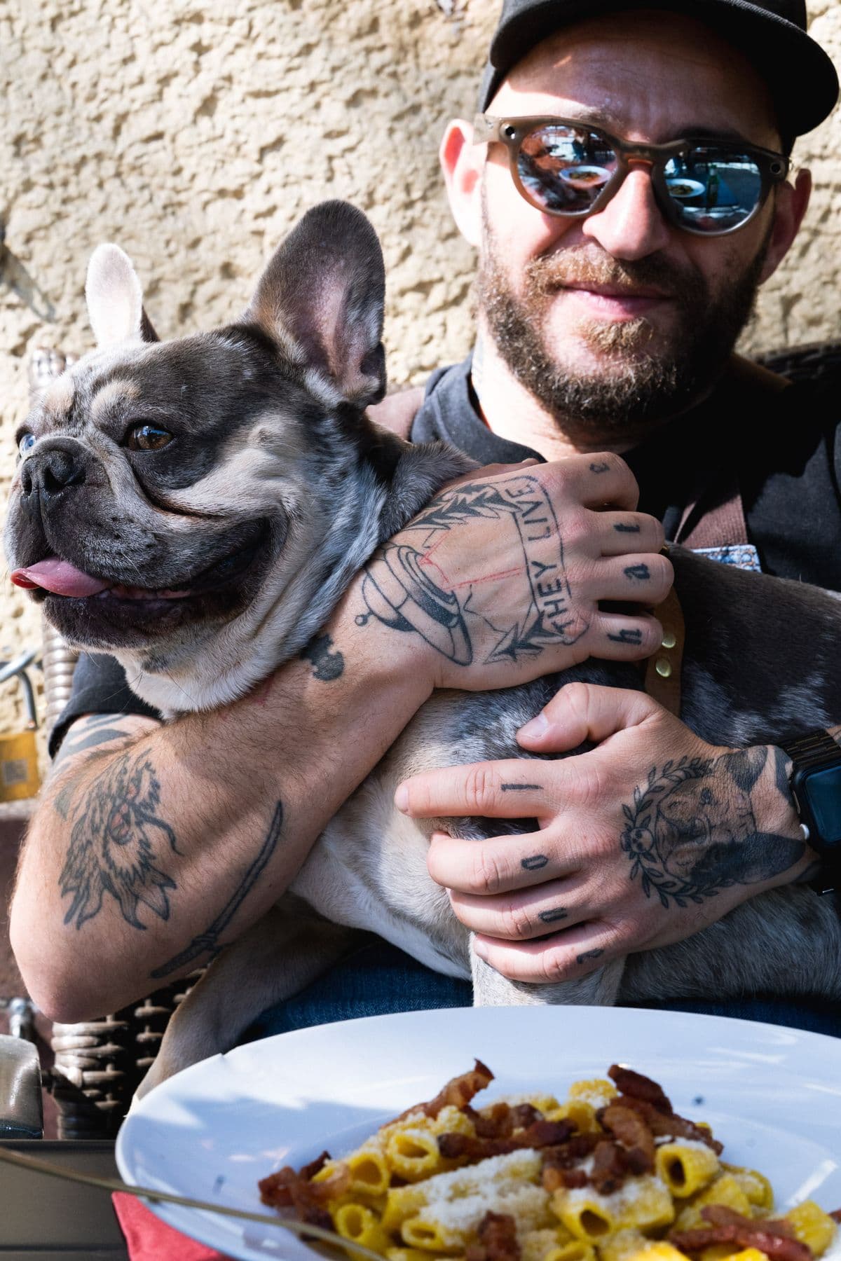 Fred, die Französische Bulldogge von Tirelli's, im Arm von Alessandro, davor Rigatoni Carbonara
