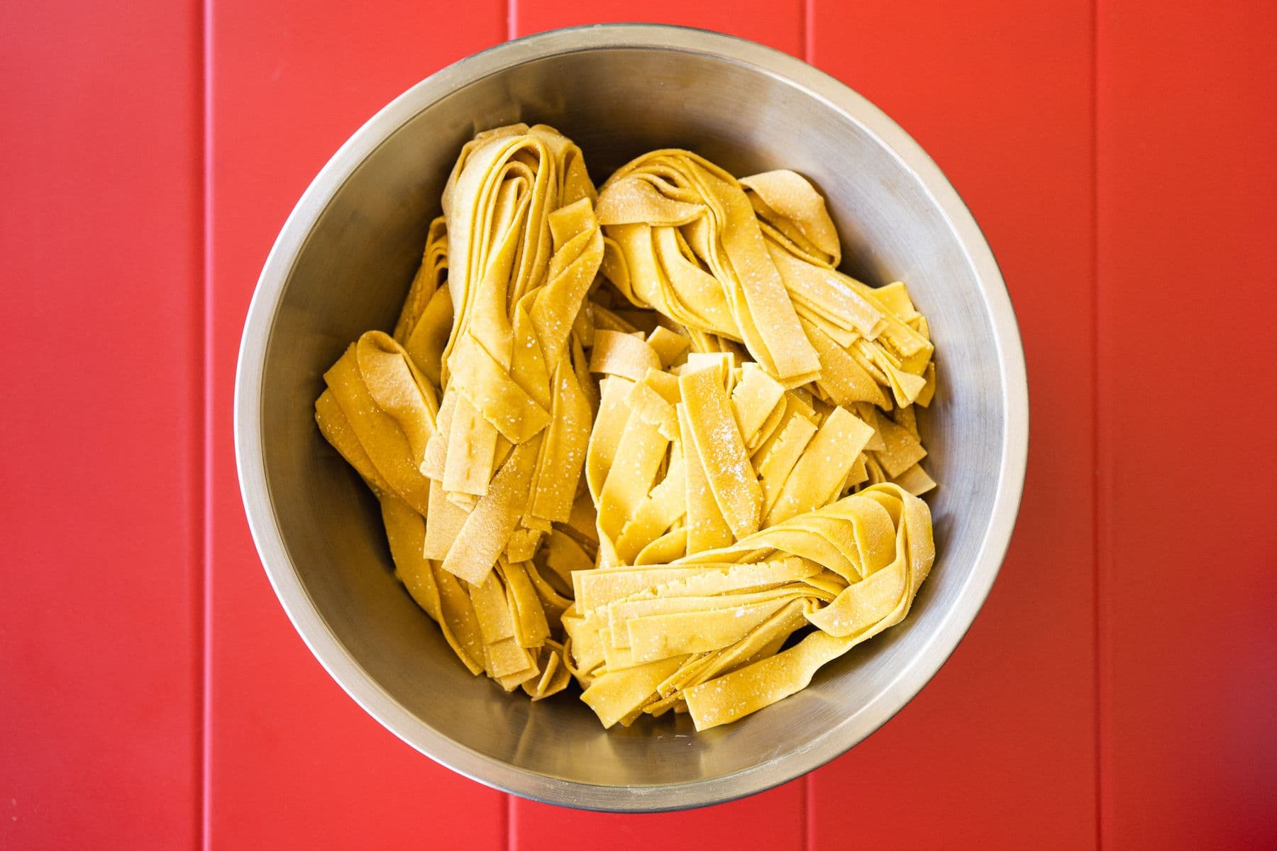 Schüssel frische Pappardelle auf rotem Tisch