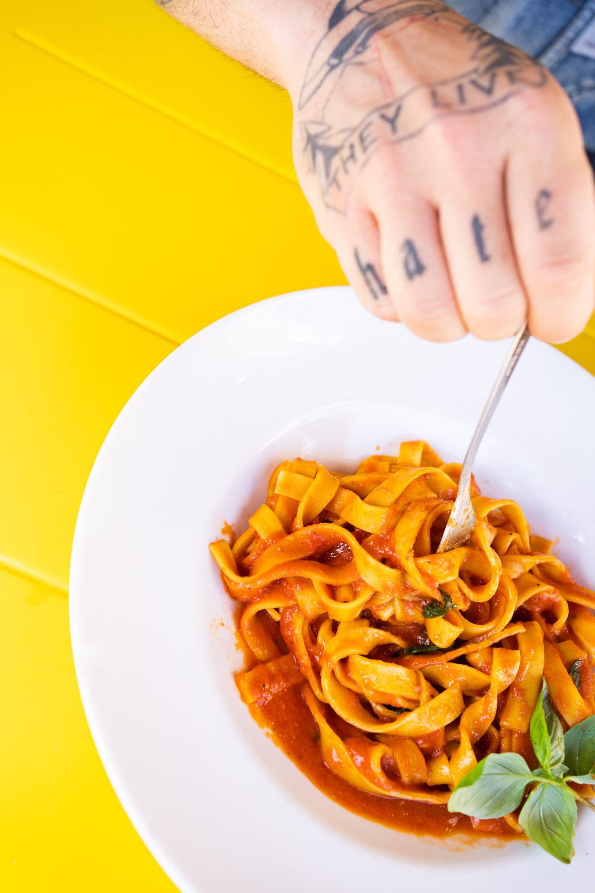 Tagliatelle al pomodoro, darüber tätowierte Fingerknöchel