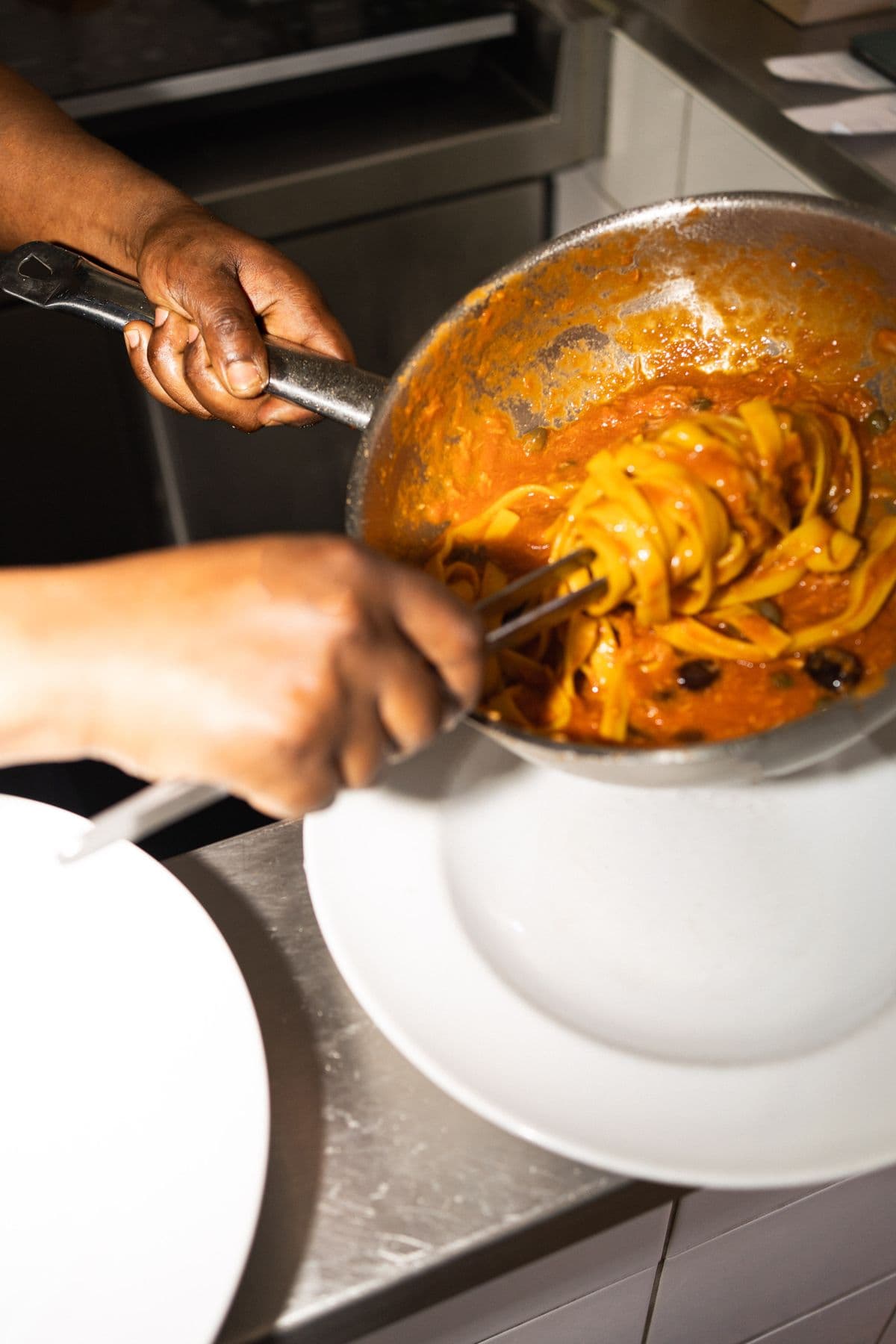 Tagliatelle werden in der Pfanne mit der Soße geschwenkt
