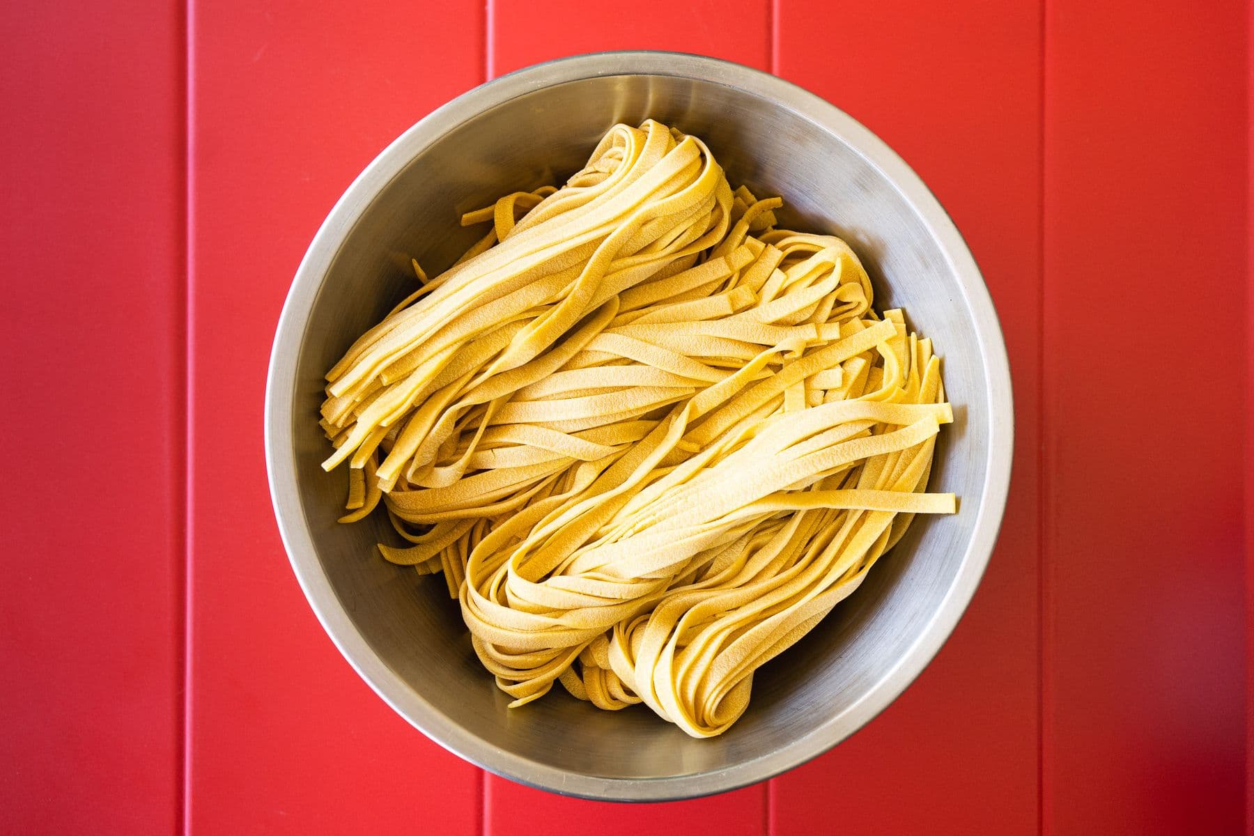 Schüssel frische Tagliolini auf rotem Tisch