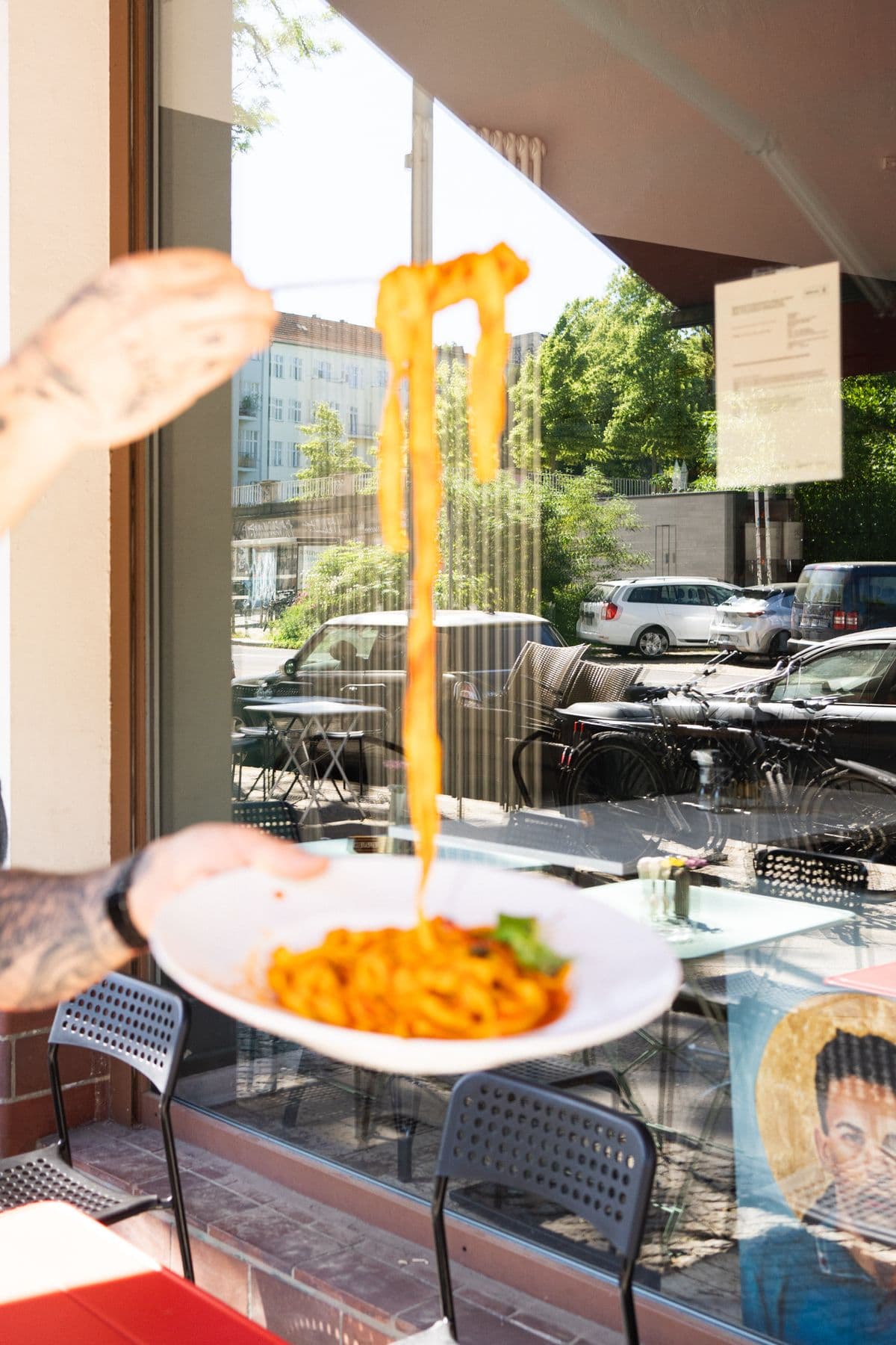 Tagliatelle werden hoch über den Teller gehoben, vor dem Fenster