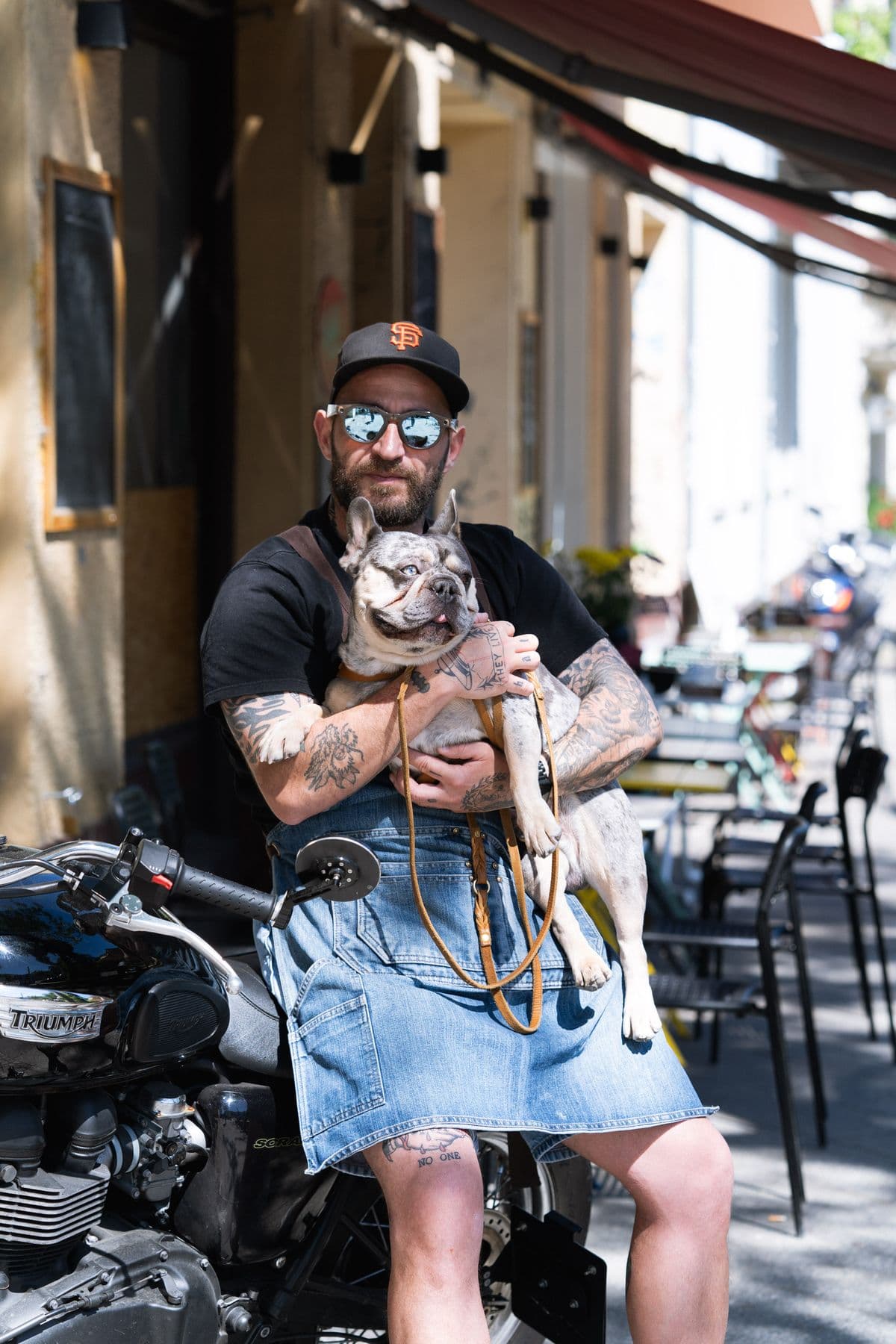 Alessandro in cap, sunglasses and denim apron on the motorbike, Fred on his lap