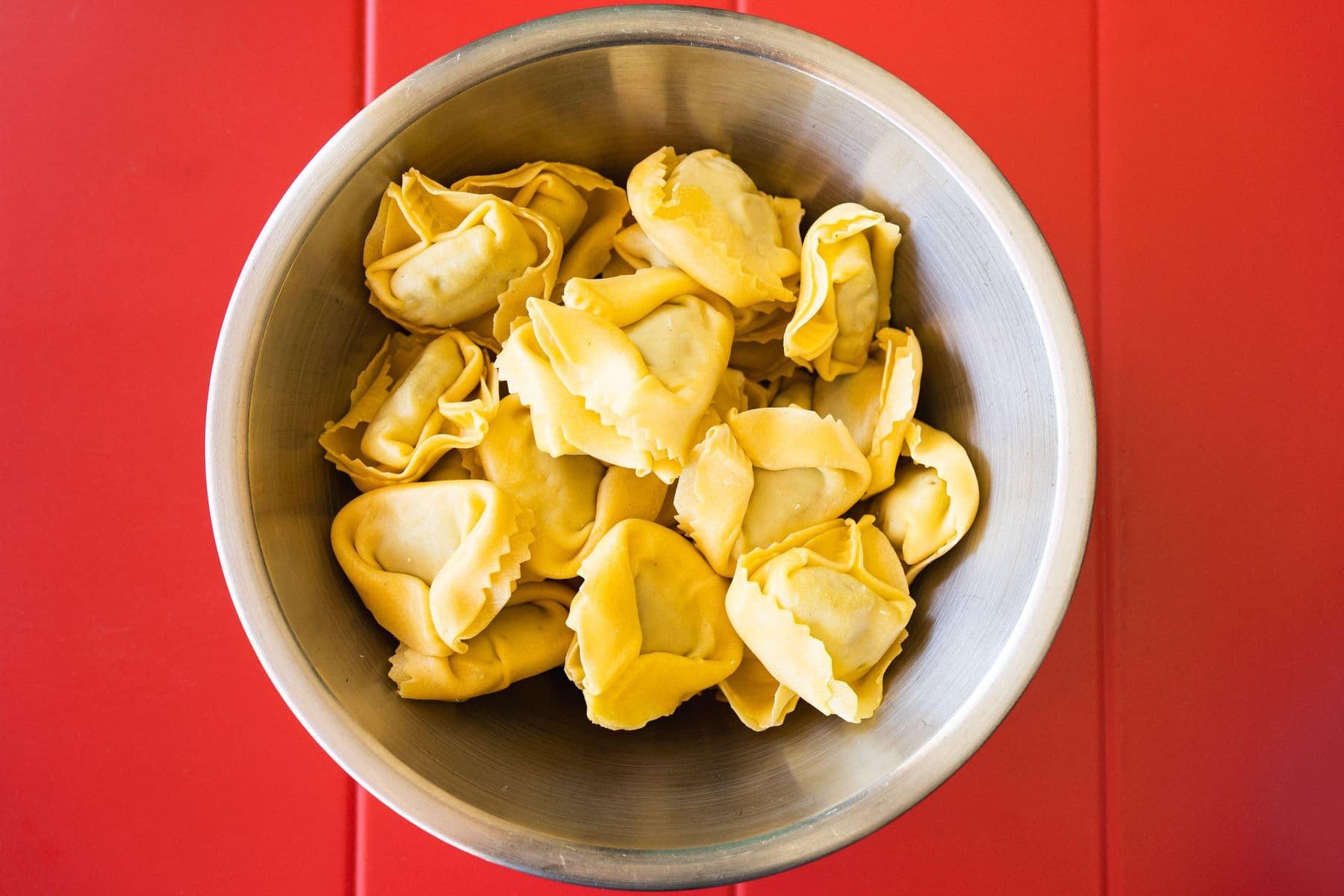 Schüssel frische Tortelloni auf rotem Tisch